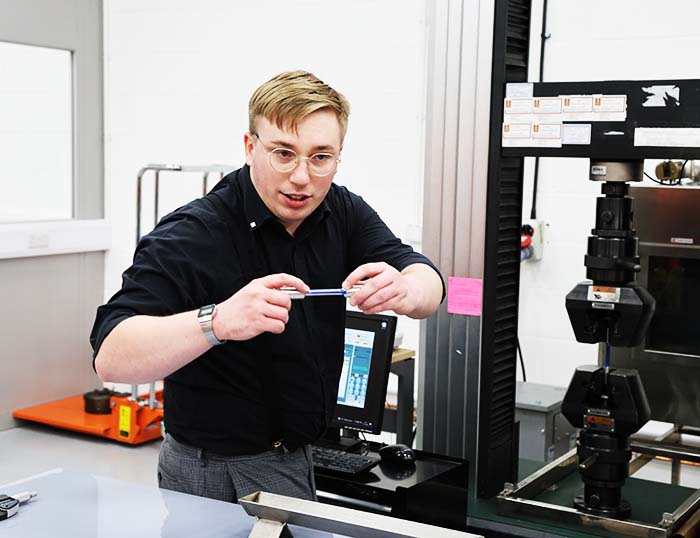 Un tecnico di laboratorio mostra una delle nostre macchine per prove di trazione.
